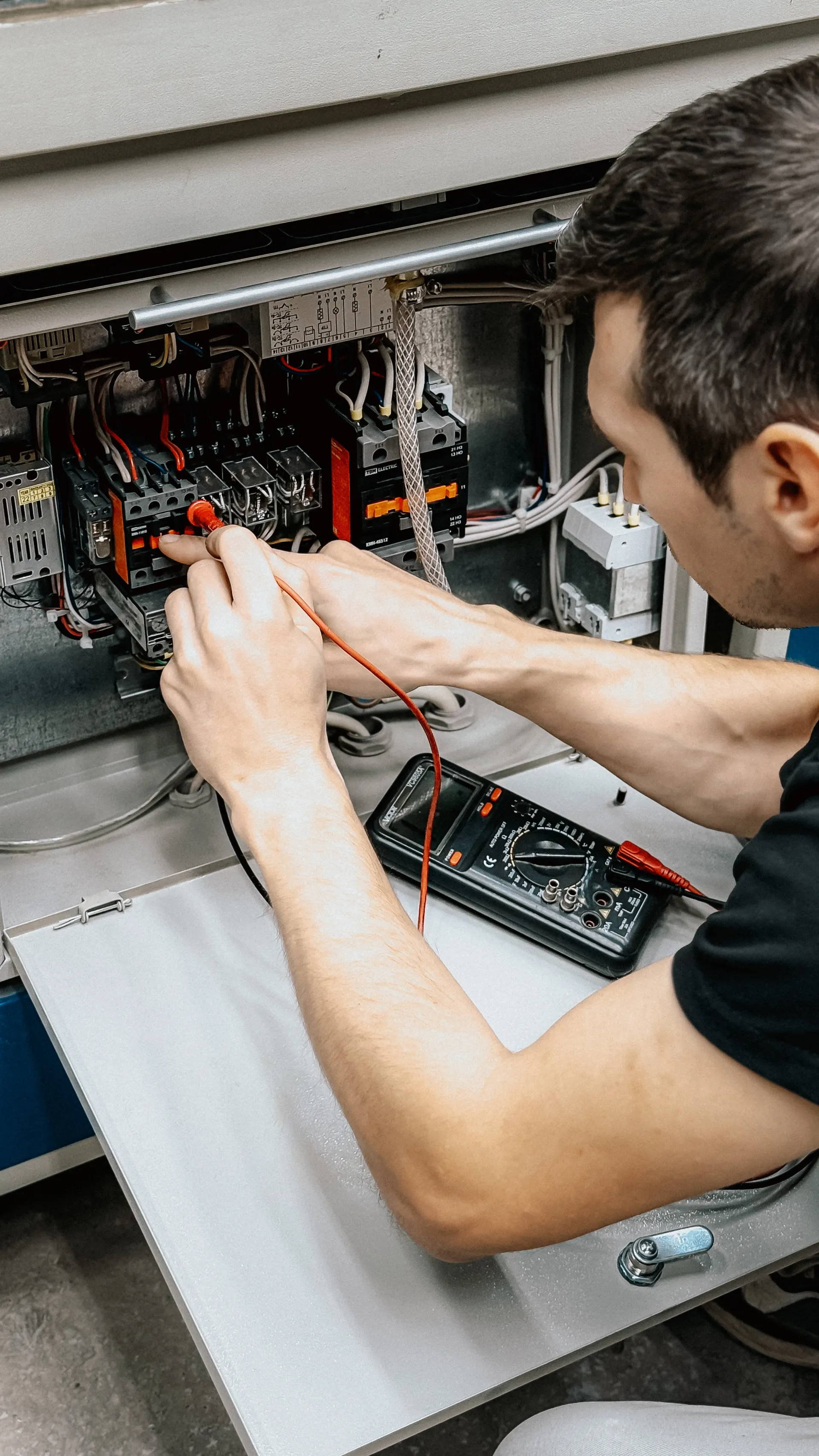 Elektrik panosunda ölçüm yapan teknisyen